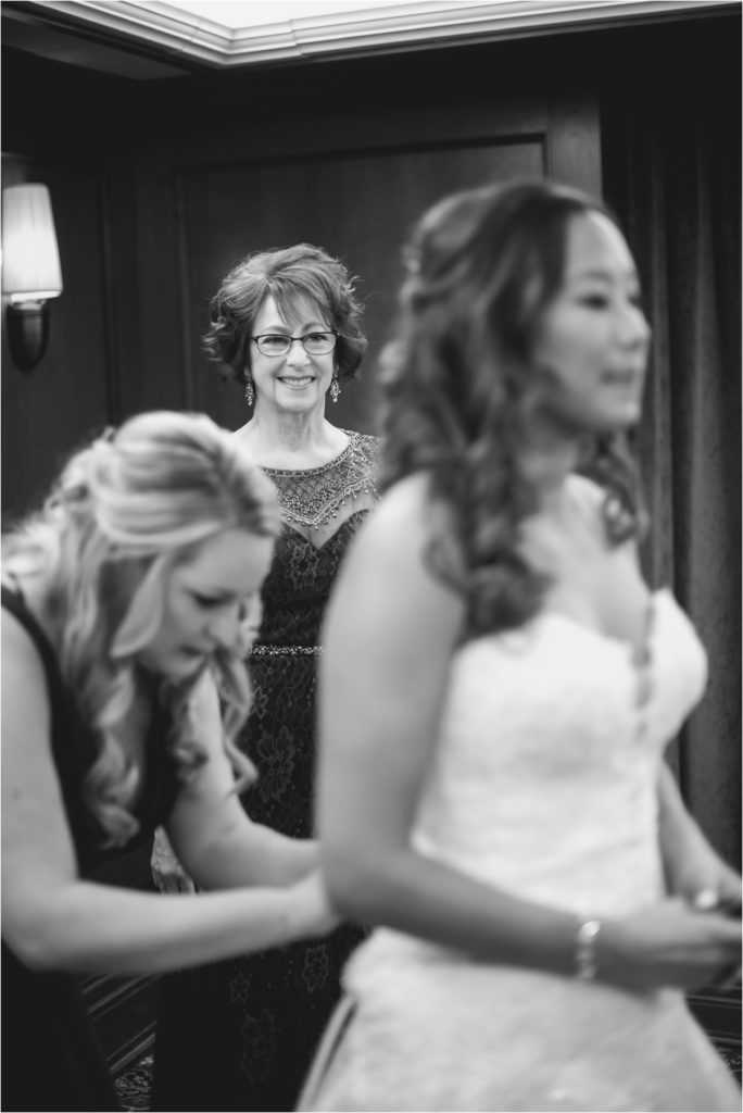 Mom watching her daughter get into wedding dress