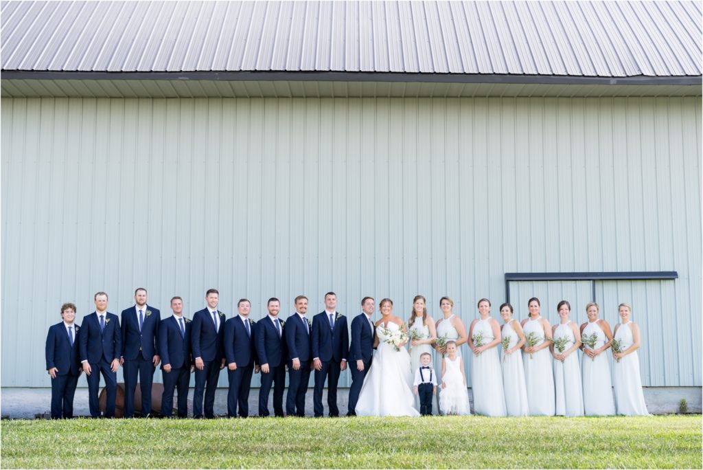 entire bridal party in front of blue barn