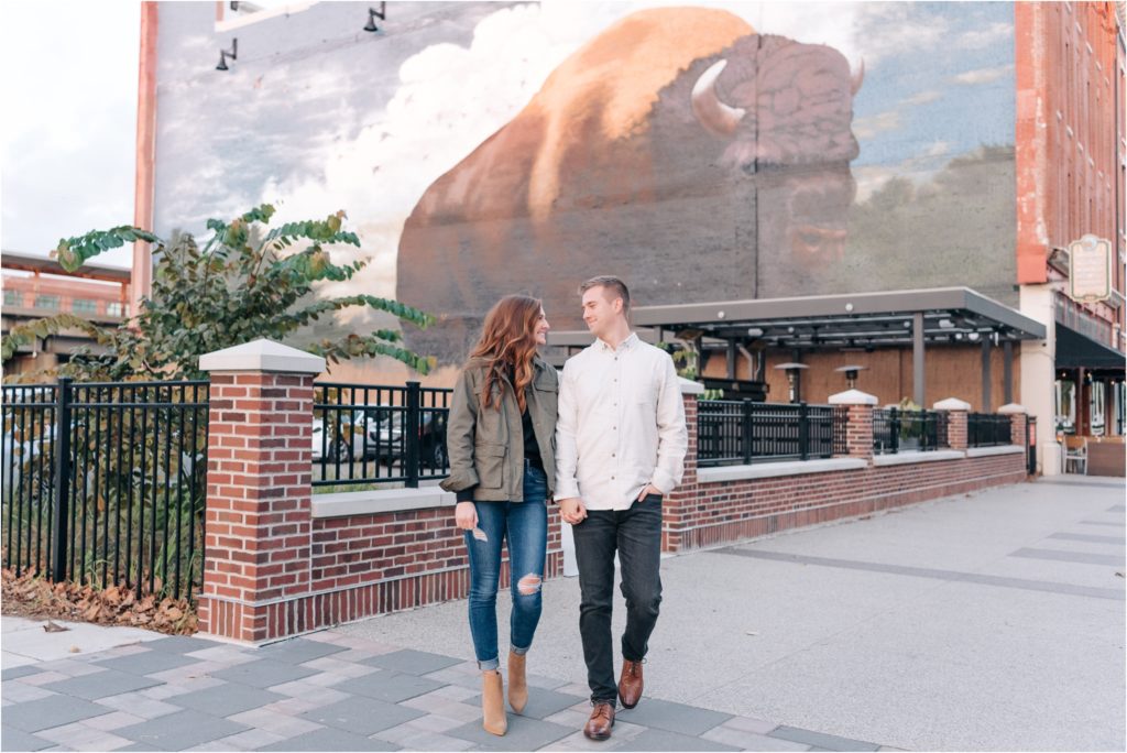 Groom walking with his fiancé in front of the bull mural fort wayne