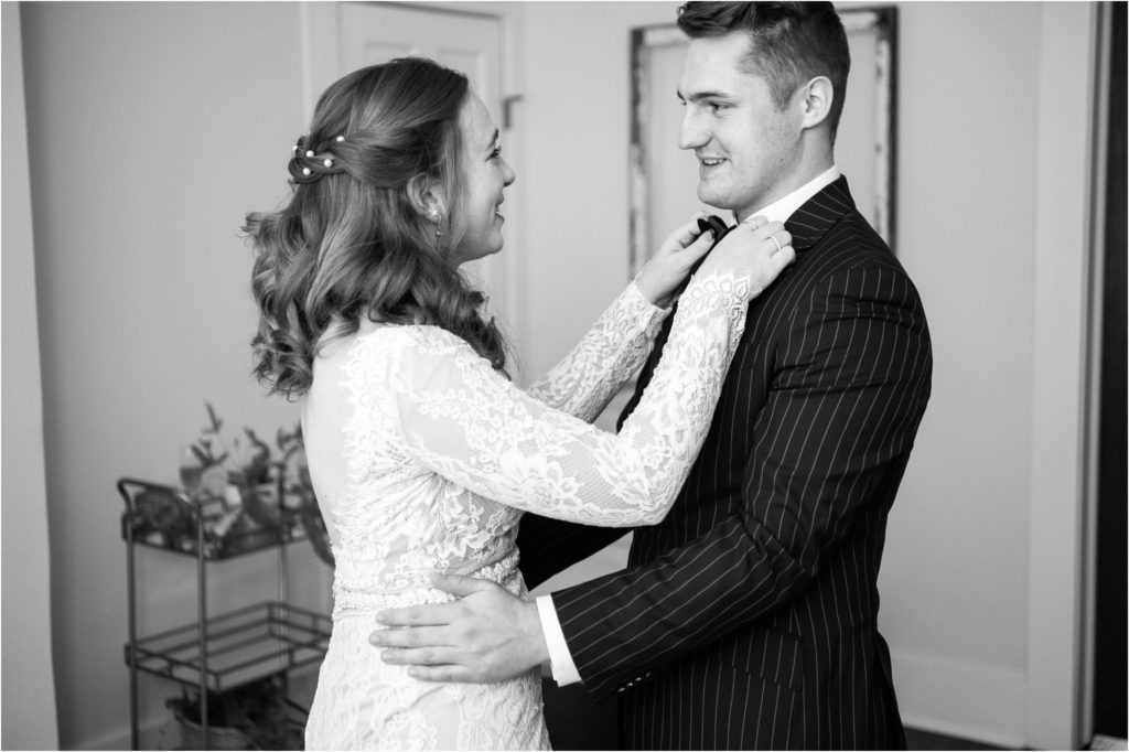 romantic black and white photos first look with the groom fixing his bow tie