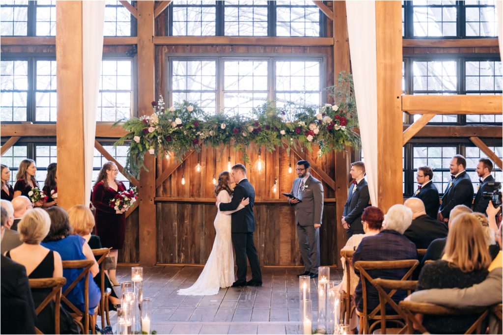 first kiss barn christmas wedding under RK floral ceremony arch mustard seed gardens barn
